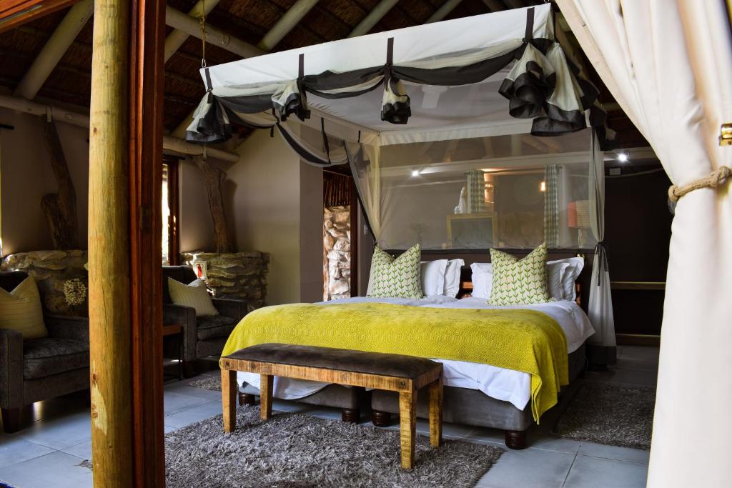 a bedroom with a canopy bed with a yellow bedspread at Mosaic Lagoon Lodge in Stanford