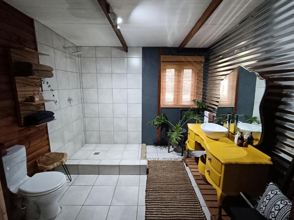 a bathroom with a yellow sink and a toilet at Fire Fly Cabin in Knysna