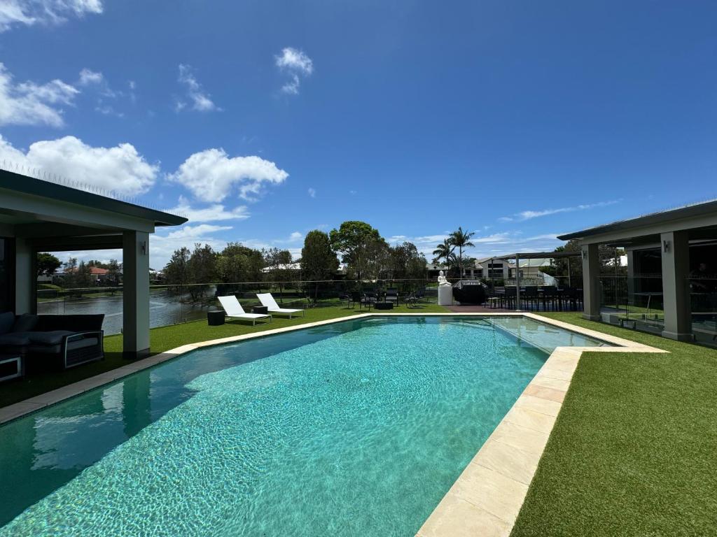 a swimming pool in a yard with chairs and a house at Lakeside Retreat in Gold Coast