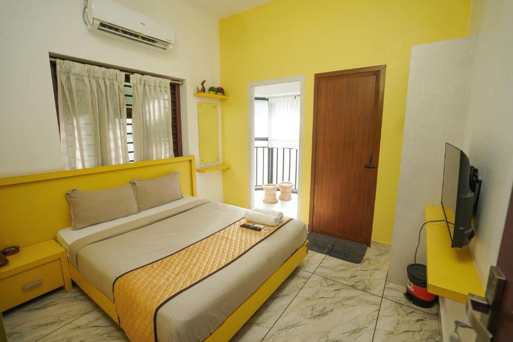 a bedroom with a large bed and a television at Twinn Waves Calicut in Kozhikode