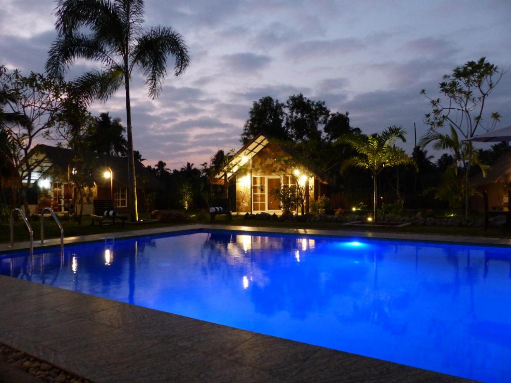 een zwembad 's nachts met een huis op de achtergrond bij Coco Village Hotel Chilaw in Chilaw