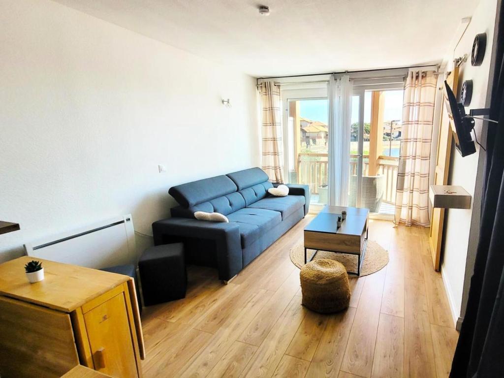 un salon avec un canapé bleu et une table dans l'établissement Résidence Le Boucanier - 2 Pièces pour 4 Personnes 614, à Vieux-Boucau-les-Bains