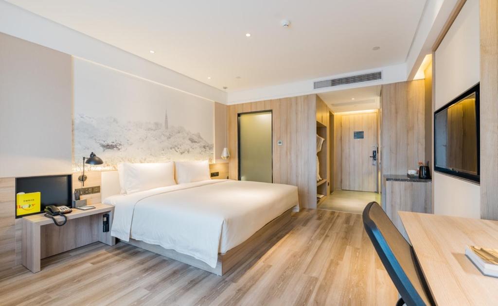 1 dormitorio con 1 cama blanca grande y escritorio en Atour Hotel Hangzhou Zhuantang Songcheng Academy of Fine Arts, en Hangzhou