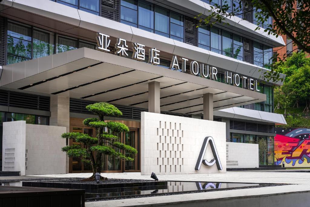 Atour Hotel Chongqing Nan'an Tea Garden New Area في تشونغتشينغ: مبنى امامه شجرة