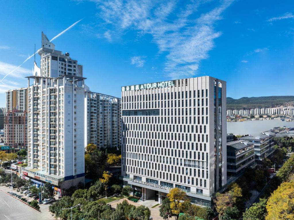 two tall buildings in a city with a river at Atour Hotel Kunming Xiaokang Avenue in Kunming