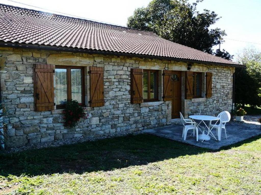 une maison en pierre avec une table et des chaises devant elle dans l'établissement Gîte de France à Saillac 2 épis - Gîte de France 2 personnes MAE-6334, à Saillac