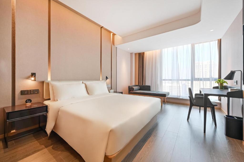 a bedroom with a large white bed and a desk at Atour Hotel Beijing North Chaoyang Road Changyingtian Street in Beijing