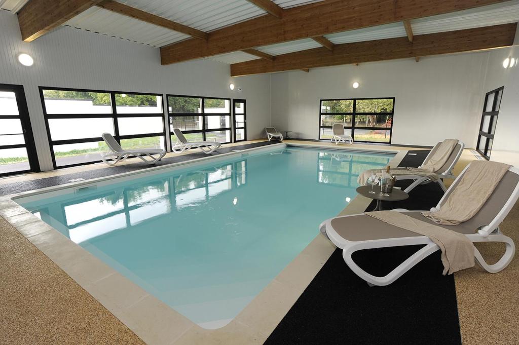 a large swimming pool with chairs and a table at Logis Auberge De La Foret in Le Gâvre