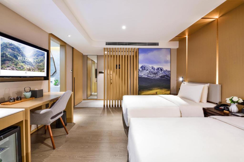 成都市にあるAtour Hotel Chengdu Jinli Hongpailou Subway Stationのベッド2台、デスク、テレビが備わるホテルルームです。
