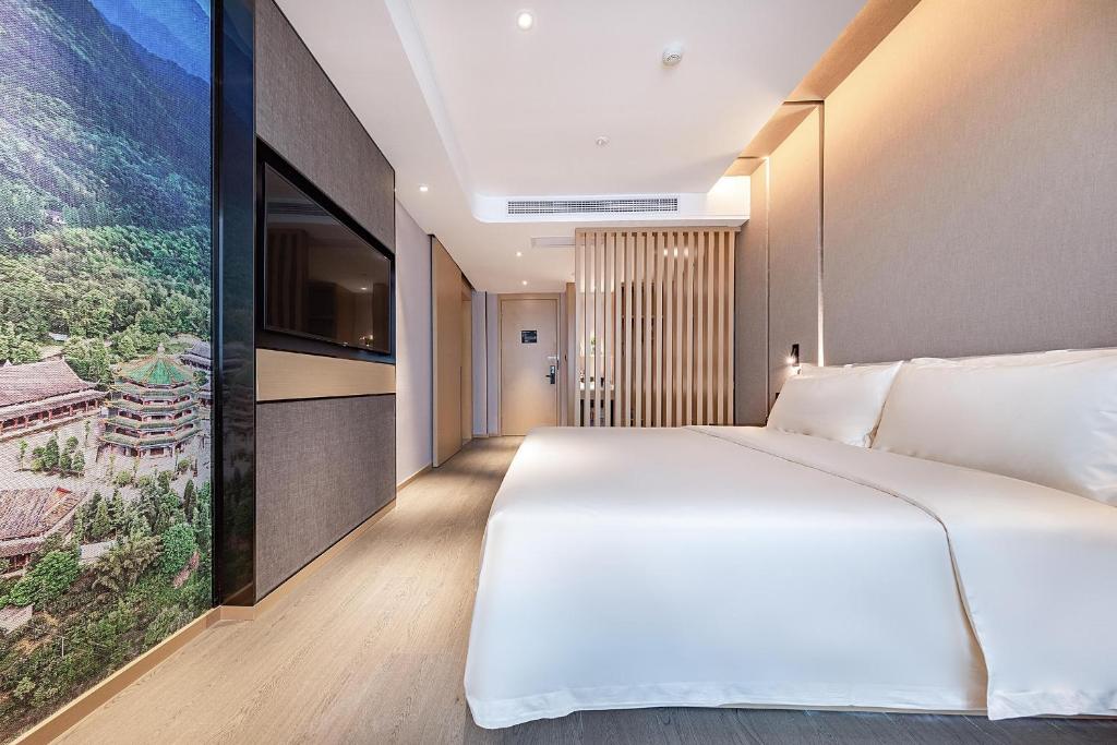 um quarto com uma grande cama branca e uma televisão de ecrã plano em Atour Hotel Chengdu Chunxi Road Tianfu Square Subway Station em Chengdu