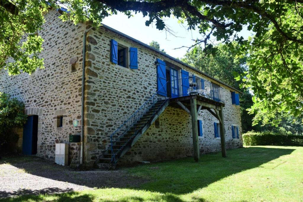 een bakstenen gebouw met blauwe ramen en een trap bij Gîte de France à Champagnac-la-Noaille 3 épis - Gîte de France 4 personn 044 in Champagnac-la-Noaille