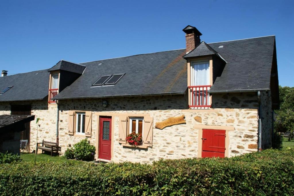 una casa de piedra con puertas rojas y techo negro en Gîte de France Pierrelise 3 épis - Gîte de France 8 personnes 194, en Espartignac