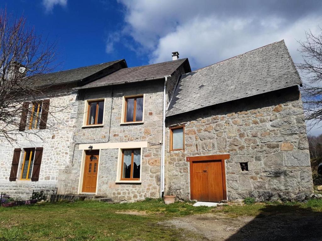 ein altes Steinhaus mit braunen Türen und Fenstern in der Unterkunft Gîte de France à Alleyrat 3 épis - Gîte de France 4 personnes MAE-9324 in Alleyrat