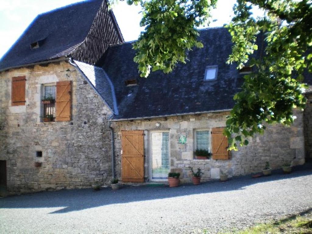 an old stone house with a black roof and brown doors at Gîte de France à Turenne 3 épis - Gîte de France 6 personnes 334 in Turenne