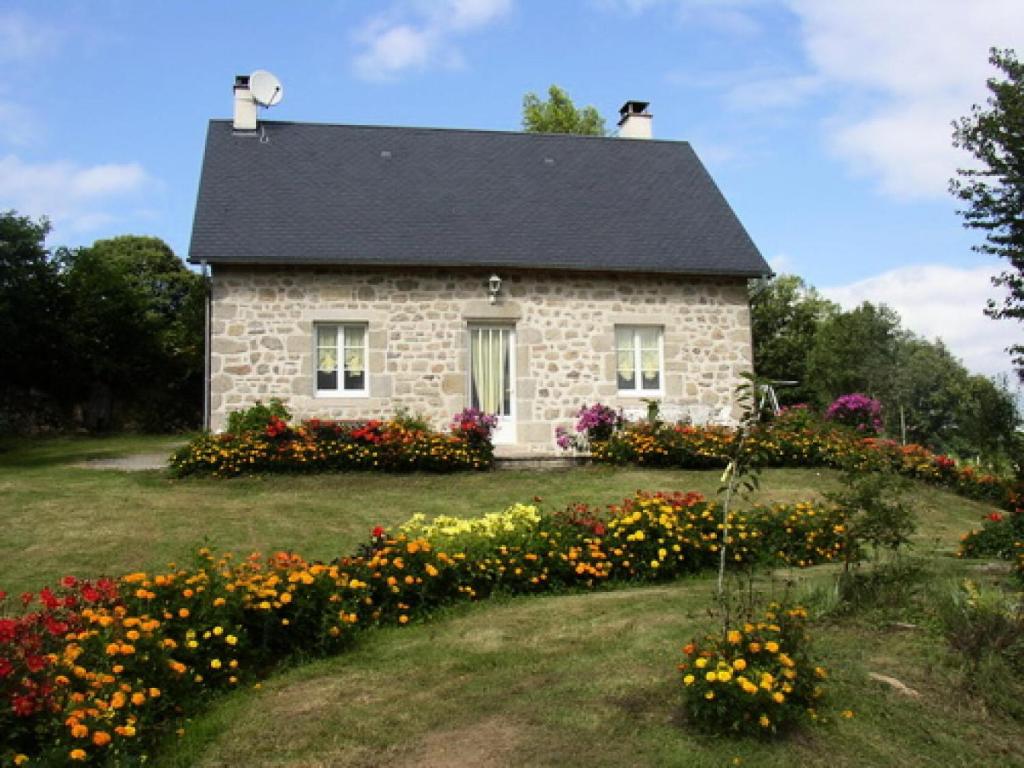 una casa de piedra con flores delante en Gîte de France à Sarroux - St Julien 3 épis - Gîte de France 6 personnes 414, en Sarroux