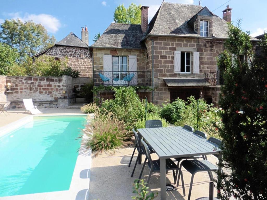 Una casa con piscina y una mesa al lado. en Gîte de France Gîte la chapelle avec piscine 3 épis - Gîte de France 6 personnes MAE-9464, en Saint-Solve