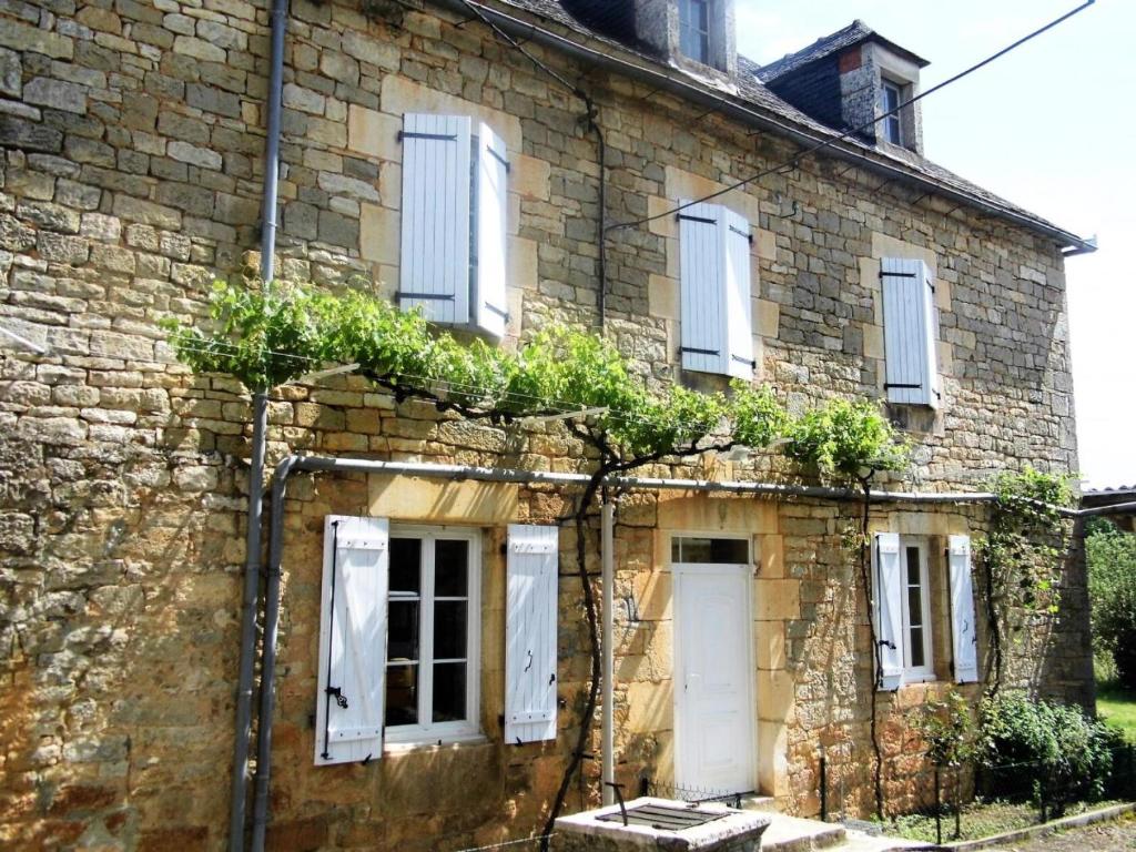 uma antiga casa de pedra com plantas na fachada em Gîte de France De baudran 3 épis - Gîte de France 6 personnes 424 