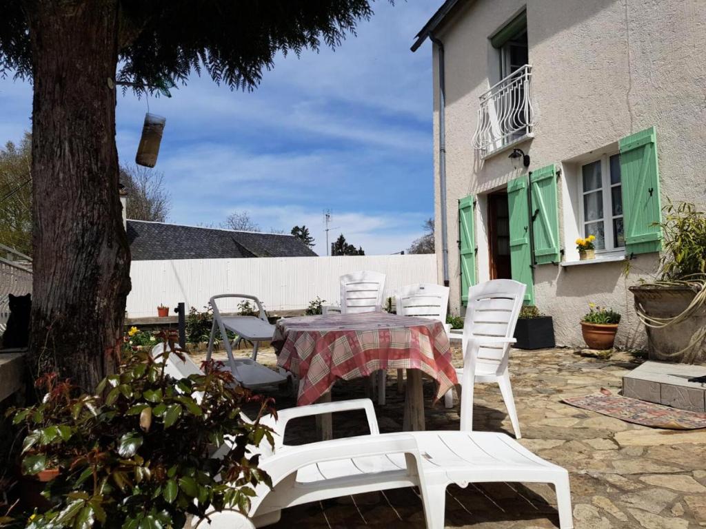 een patio met een tafel en stoelen en een boom bij Gîte de France à Albussac 3 épis - Gîte de France 2 personnes 614 in Albussac