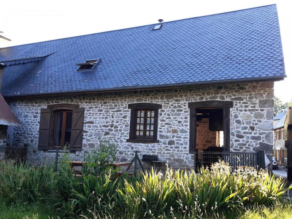 an old stone house with a blue roof at Gîte de France à Lamazière-Haute 2 épis - Gîte de France 5 personnes MAE-9934 in Lamazière-Haute