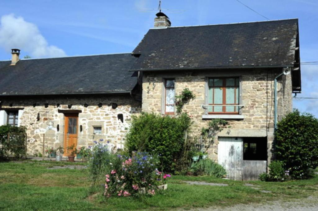 una antigua casa de piedra con techo negro en Gîte de France à Soudaine-Lavinadière 3 épis - Gîte de France 5 personn 954, en Soudaine-Lavinadière