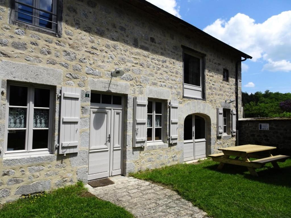 un edificio de piedra con puertas blancas y mesa de picnic en Gîte de France Maison raymond épis - Gîte de France 804 en Saint-Angel