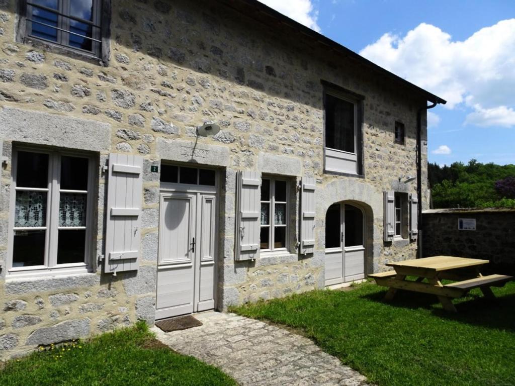 a stone building with white doors and a picnic table at Gîte de France Maison raymond 3 épis - Gîte de France 12 personnes MAE-9804 in Saint-Angel