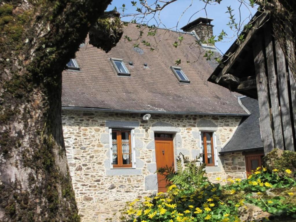 una vecchia casa in pietra con una porta arancione di Gîte de France Gite de la genette 3 épis - Gîte de France 8 personnes 024 a Beyssenac