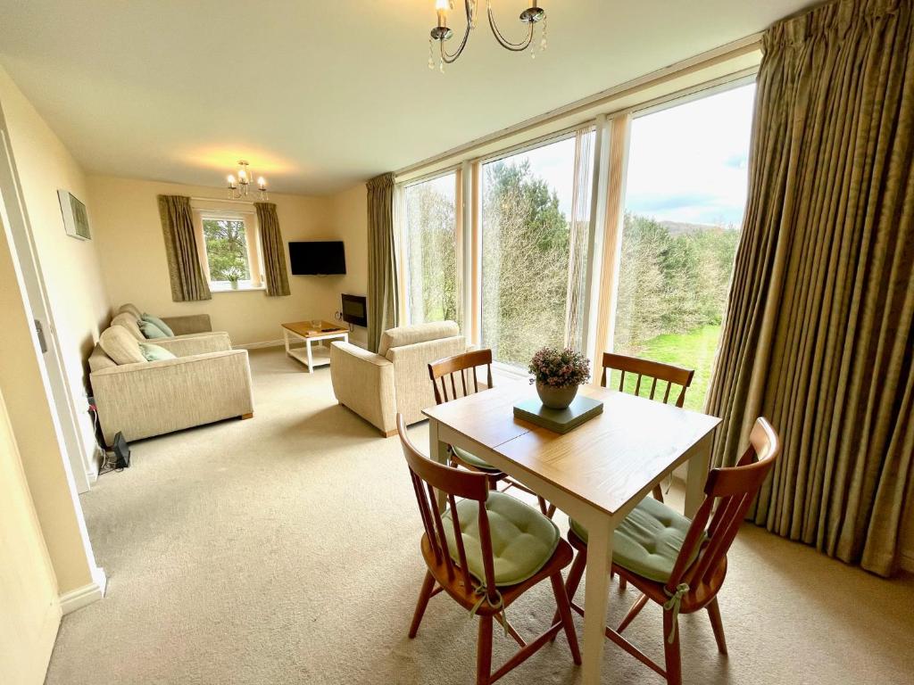 a living room with a table and chairs and a large window at Otterhole Barn Holiday Apartment in Buxton