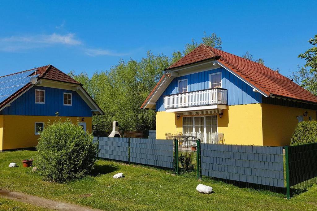 a blue and yellow house behind a fence at Cottages at the Kummerower See Verchen in Verchen
