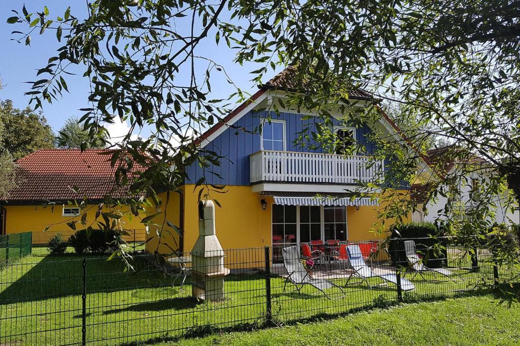 ein gelbes und blaues Haus mit einem Zaun in der Unterkunft Cottages at the Kummerower See Verchen in Verchen