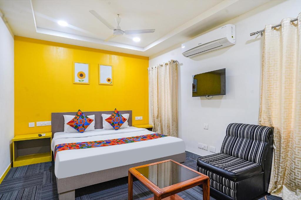 a bedroom with a bed and a chair and a tv at FabExpress Luxury Inn in Hyderabad