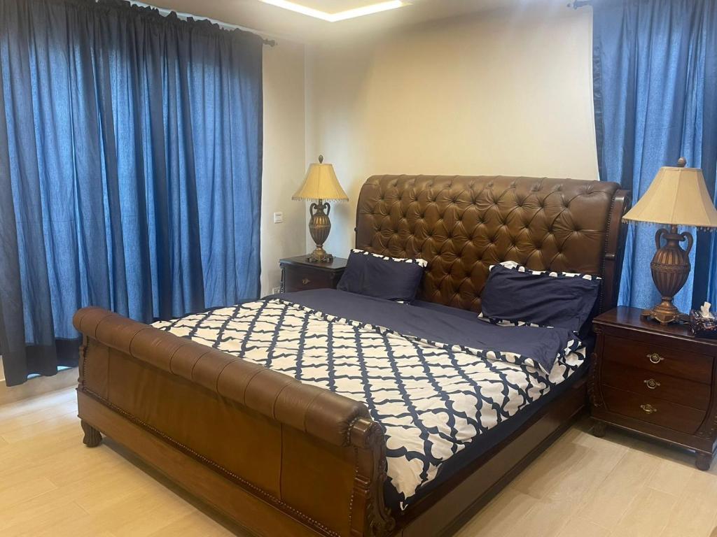 1 dormitorio con 1 cama grande y cortinas azules en Grey Orchard Homestay - A Family Place en Lahore