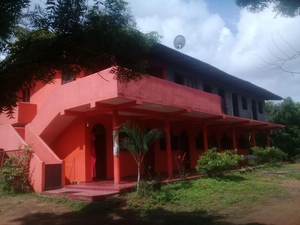 a red building with a tree in front of it at Sayonara Resort in Hambantota