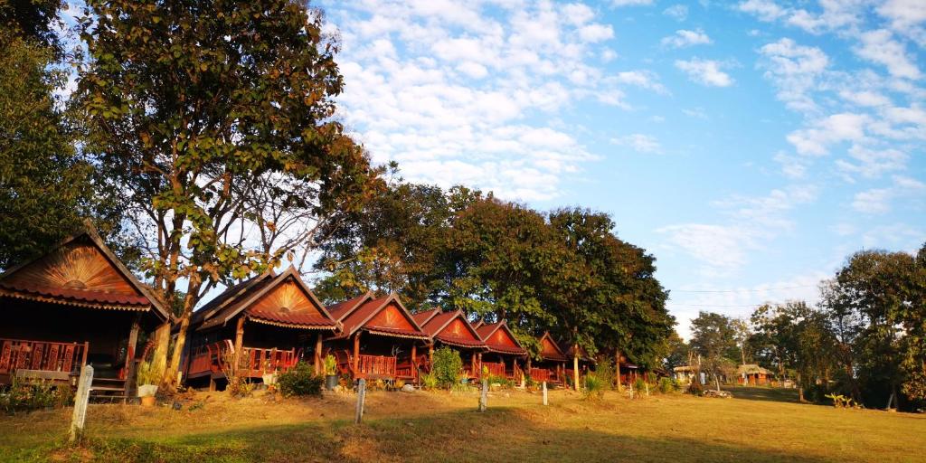 a building with red roofs and trees in a field at ปายสามหมอก in Pai