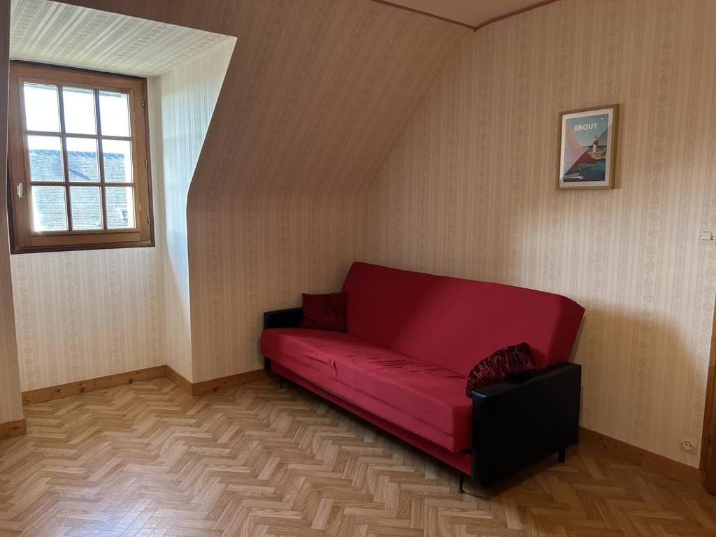 - un canapé rouge dans une chambre avec fenêtre dans l'établissement 802 - Maison avec jardin à quelques pas du centre bourg d'Erquy, à Erquy