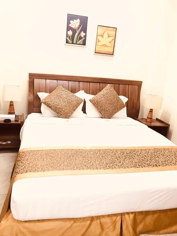 ein Schlafzimmer mit einem großen weißen Bett mit Kissen in der Unterkunft The Address Served Apartments in Al Jubayl