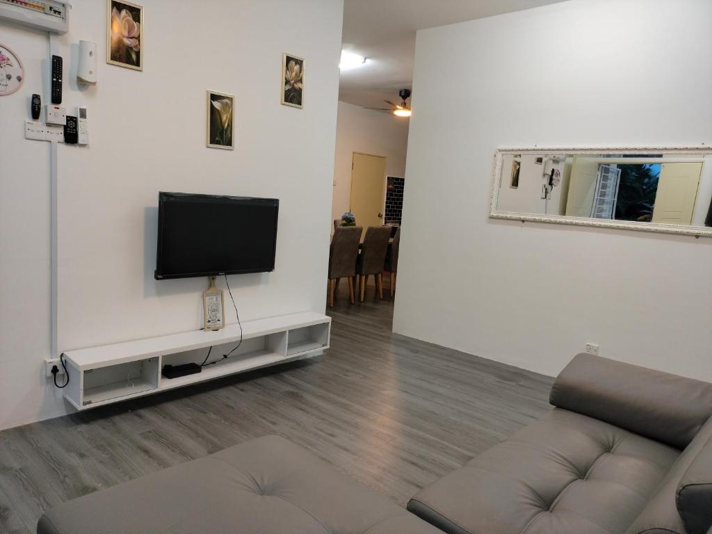 sala de estar con sofá y TV en la pared en AZK HOMESTAY, en Sungai Besar