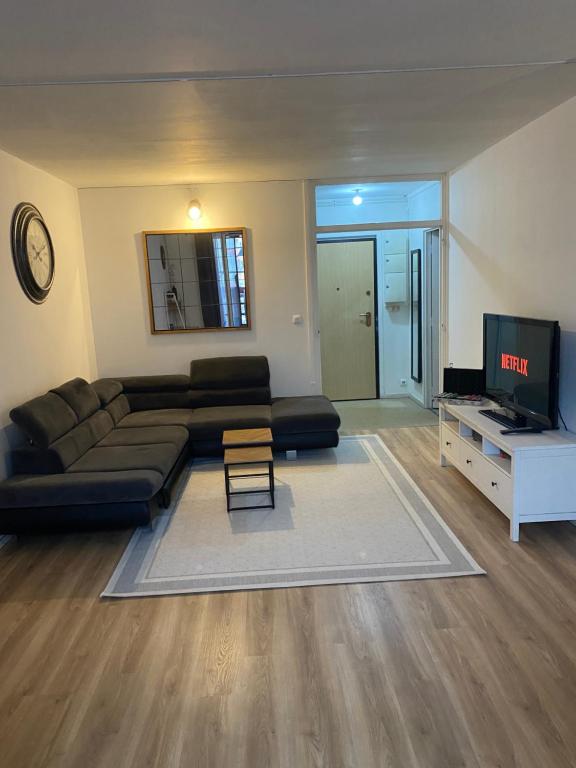 uma sala de estar com um sofá preto e uma televisão em Paris- Stade de France -CDG-Disney em Saint-Denis