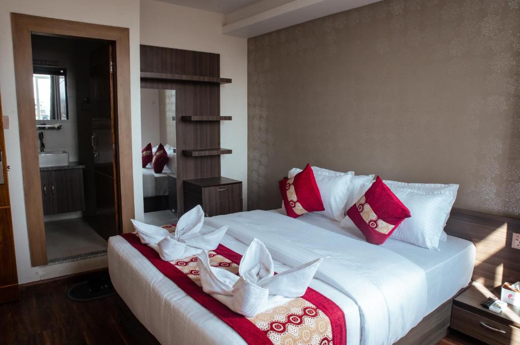 1 dormitorio con 1 cama grande con almohadas rojas y blancas en Kusum Airport Hotel, en Katmandú
