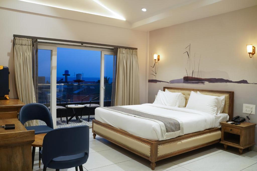 a bedroom with a bed and a desk and a balcony at Ariena by Spree Hotels Goa in Morjim