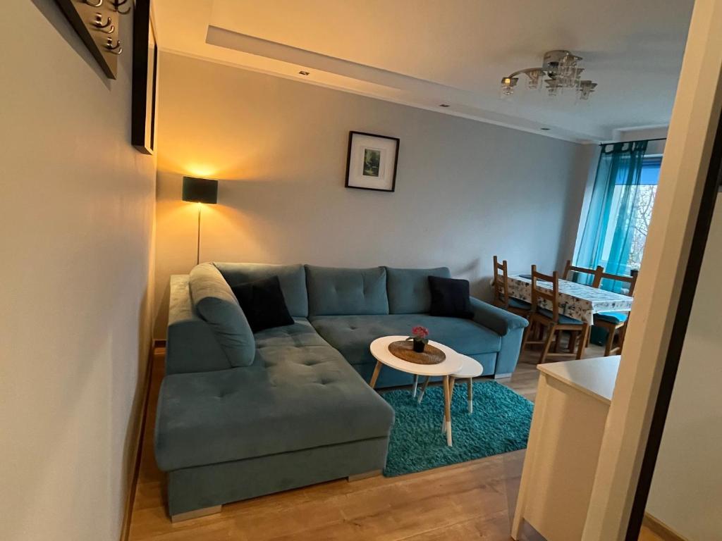 a living room with a blue couch and a table at Apartament TURKUSOWY in Kalisz