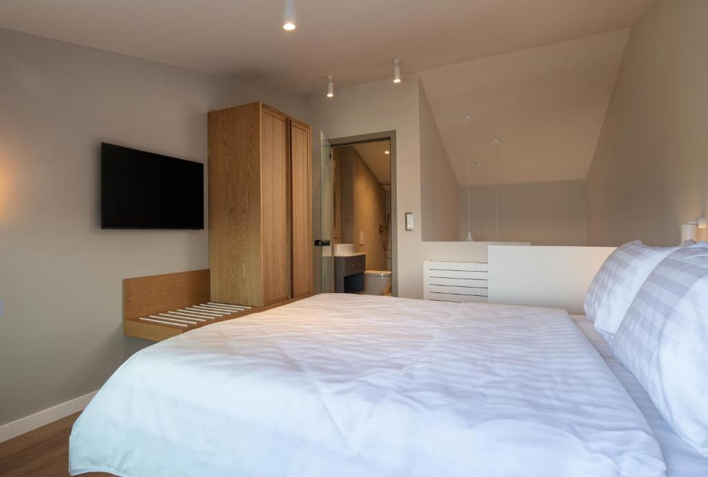 a bedroom with a large white bed and a flat screen tv at Oniro Boutique Hotel in Toroni