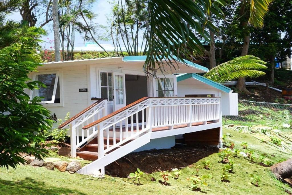 Casa blanca pequeña con porche y escaleras en Lovely 3 BR Ocean View Villa, en Cap Estate