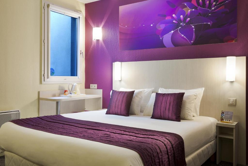 a bedroom with a large bed with purple walls at Comfort Hotel Orléans Olivet in Olivet