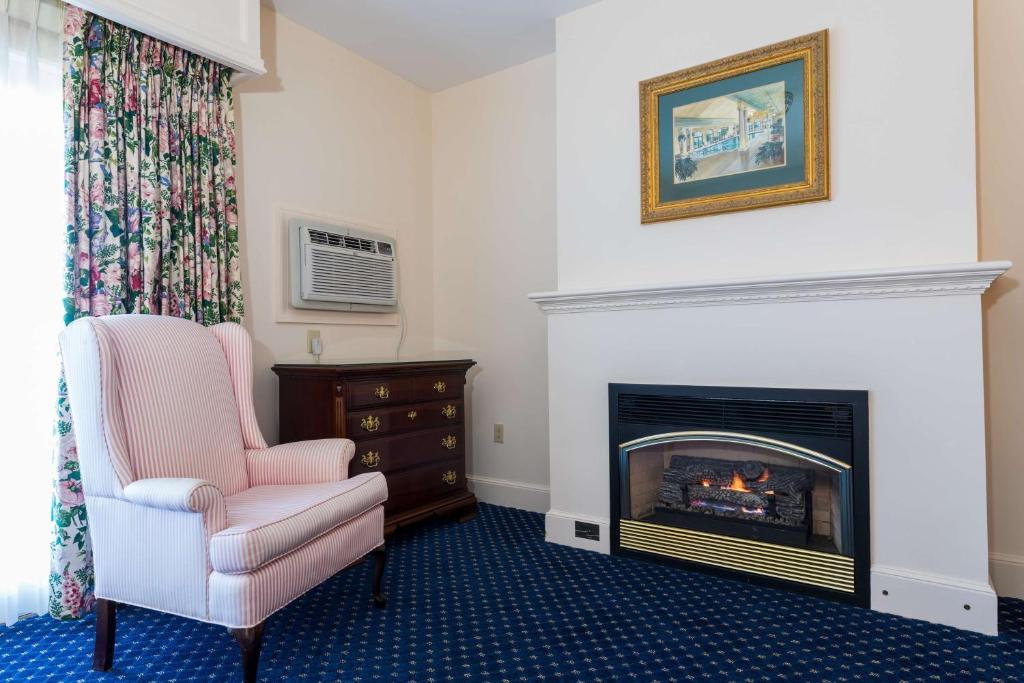 a living room with a fireplace and a chair at Bluenose Inn - Bar Harbor Hotel in Bar Harbor
