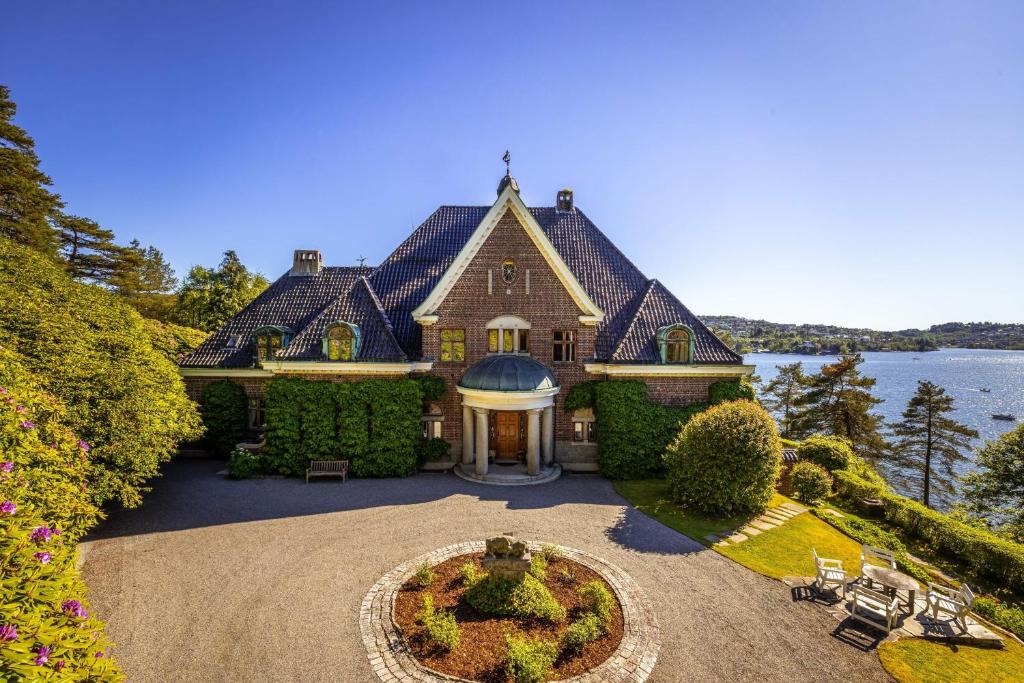 une grande maison avec un jardin en face de celle-ci dans l'établissement Unique Victorian Villa with private coastline, à Bergen
