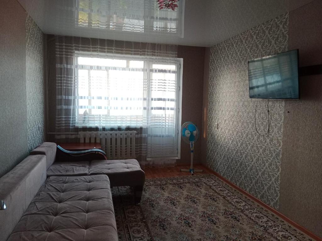 - un salon avec un lit et une fenêtre dans l'établissement Темиртау 7 микрорайон 1а, à Temirtaū