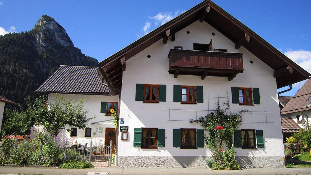 Biały dom z zielonymi oknami i górą w obiekcie Gästehaus Unruh w mieście Oberammergau