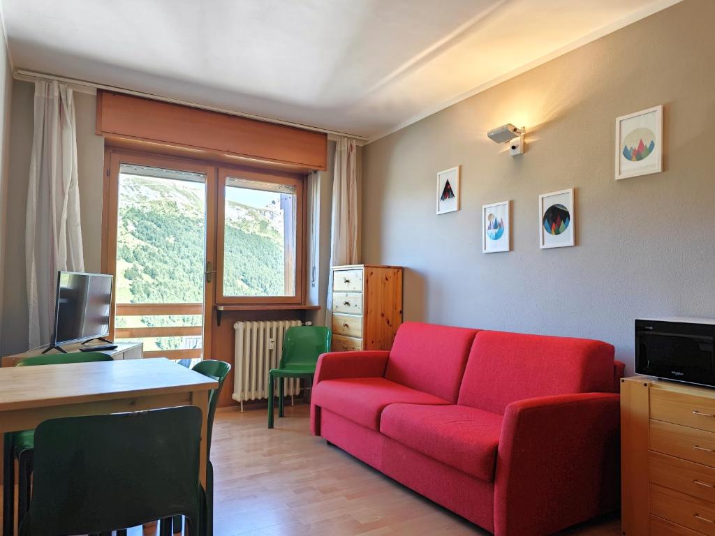 uma sala de estar com um sofá vermelho e uma secretária em Hostdomus - Color Apartment em Sestriere