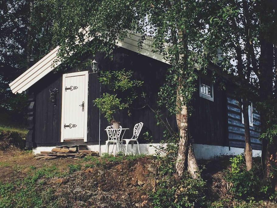 a table and two chairs in front of a cabin at Sjarmerende tømmerhytte på gårdstun 